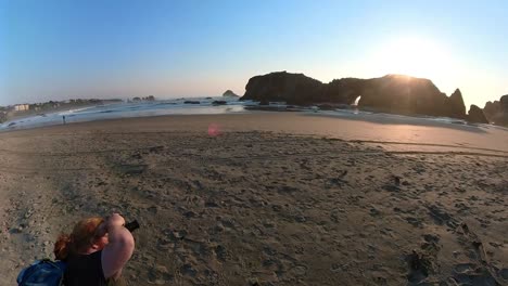 A-red-haired-photographer-kneels-filming-a-sea-cave