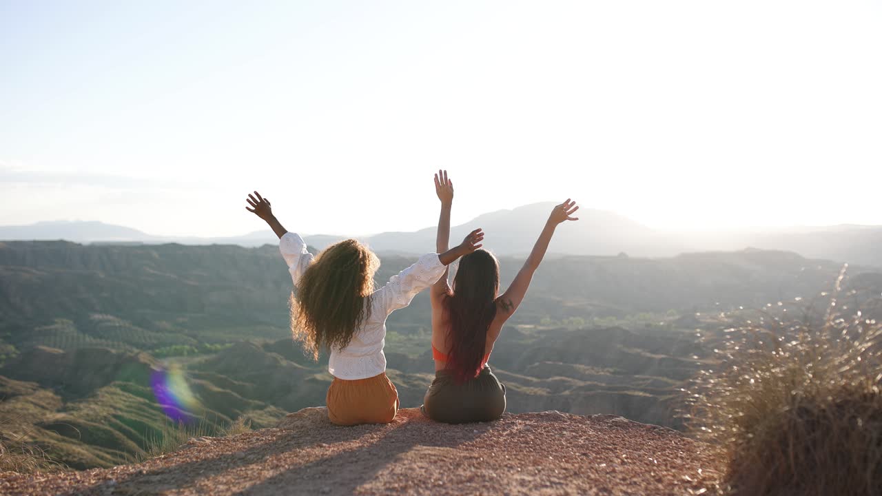 Two friends celebrating freedom on a mountain top at sunrise