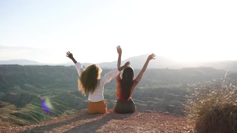 two friends celebrating freedom on a mountain top at sunrise