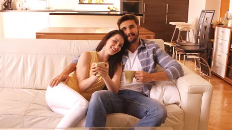 una pareja relajándose en el sofá y tomando café.