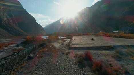biker solo riding under a beautiful evening sunlight in a majestic mountain landscape. cinematic aerial from himalayan valley in spiti, asia