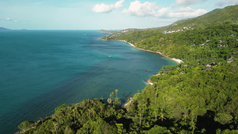 Establishing-drone-shot-of-beautiful-coastline-of-Koh-Samui-during-golden-sunset---Green-mountains-and-blue-ocean