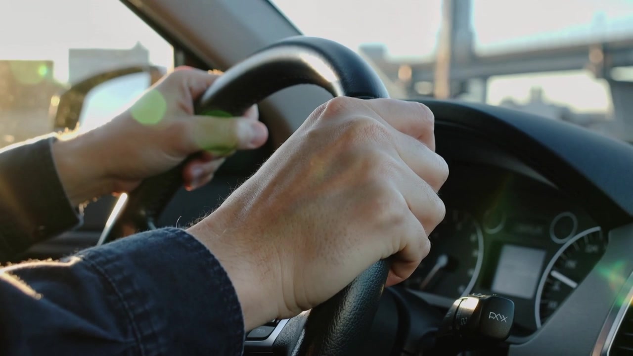 Approaching overpass as steering hands adjusting grip for control on roadway, with leather wheel