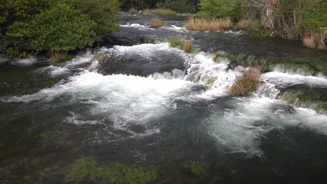 agua que fluye de un nivel a otro con plantas verdes y marrones claras intercaladas en el parque nacional krka en croacia a ¼ de velocidad