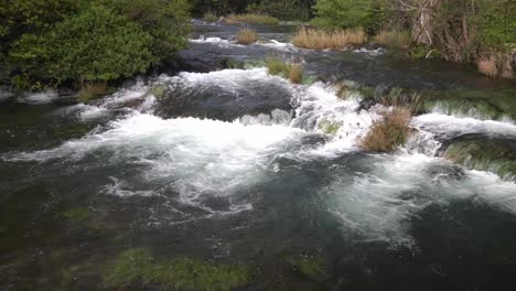 Water-flowing-from-one-tier-to-another-with-green-and-light-brown-plants-interspersed-at-Krka-National-Park-in-Croatia-at-¼-speed