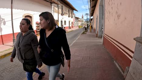two women walking on cobblestone street in a latin american town