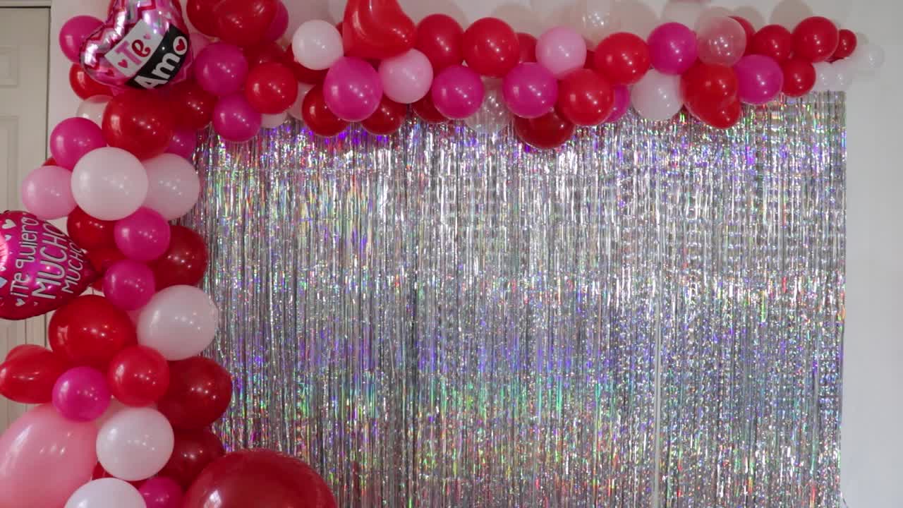 Man decorating wall with balloons and fringes for Valentine, timelapse