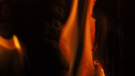 beautiful dynamic flames licking and burning the wood in a dark fireplace with orange flames