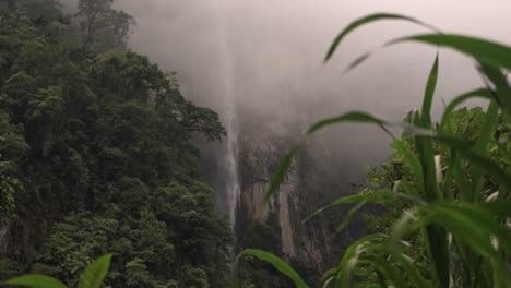 a close-up and atmospheric video frame showcases a powerful waterfall cascading down a sheer cliff, with its top obscured by mist