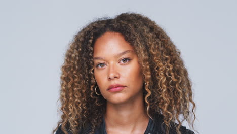 head and shoulders studio shot of woman looking at camera with serious expression in slow motion