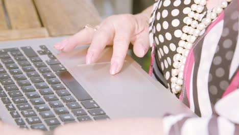 Close-up-on-elderly-woman-hands-as-she-scrolls-and-clicks-on-a-laptop