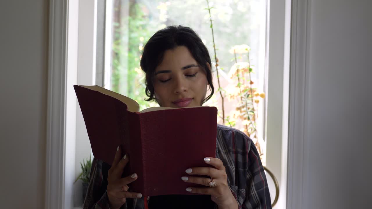 joven adulta puertorriqueña leyendo la biblia sagrada en casa inspirada por las escrituras