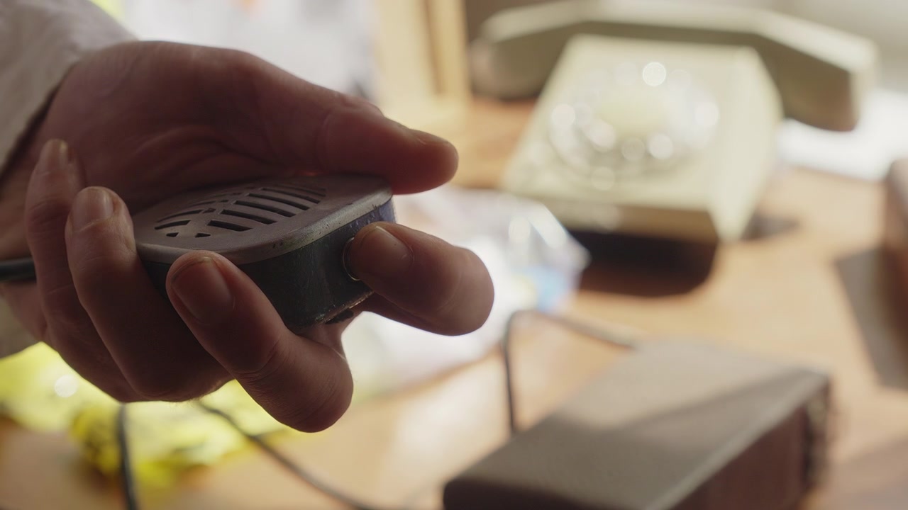 Gros plan sur un détective transmettant des informations via un microphone radio. Évoque la surveillance, la communication des forces de l'ordre, les opérations coordonnées et le travail d'équipe d'enquête