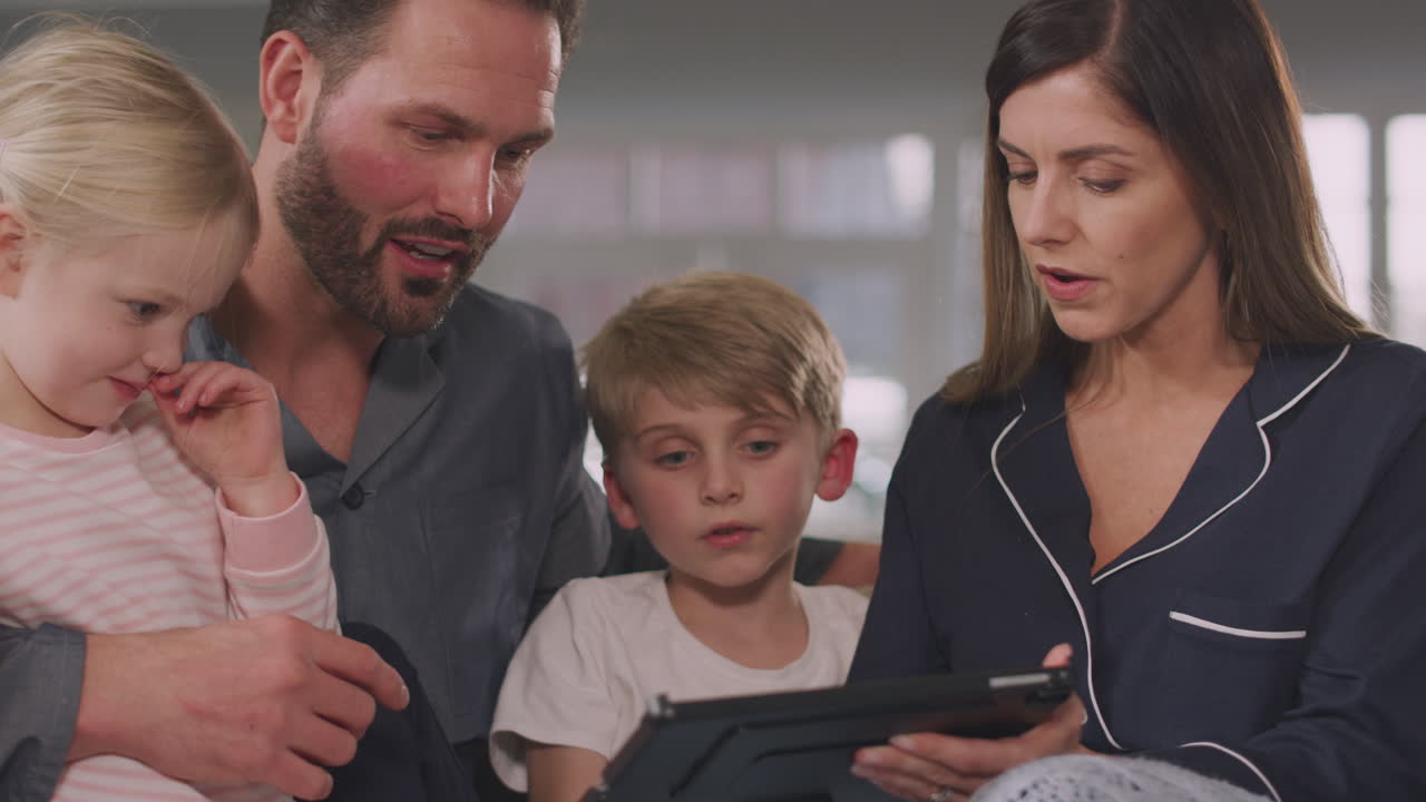 Famiglia Sorridente Vestita Seduta sul Divano che si Diverte Usando un Tablet Digitale Insieme