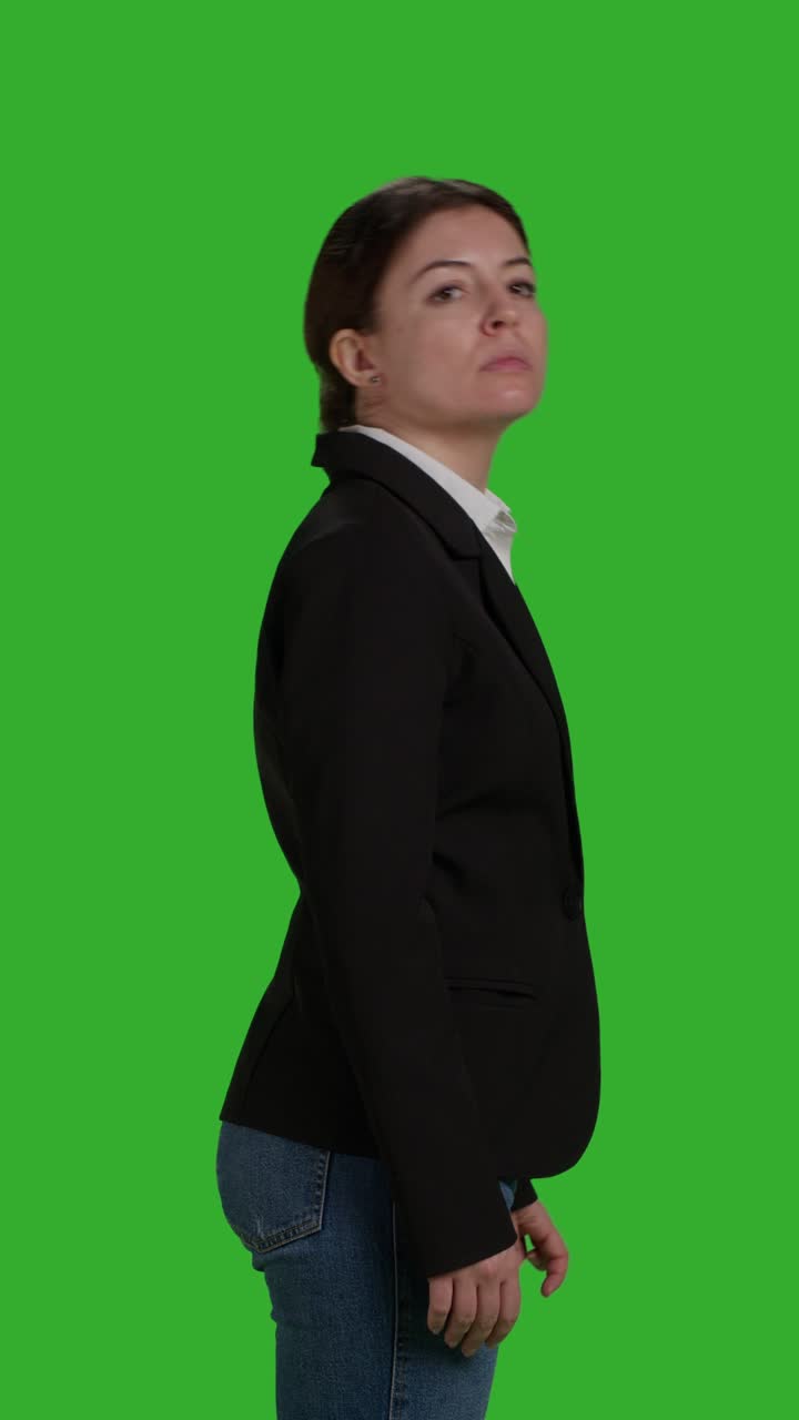 Video verticale: primo piano laterale di una donna d'affari concentrata in piedi su greenscreen