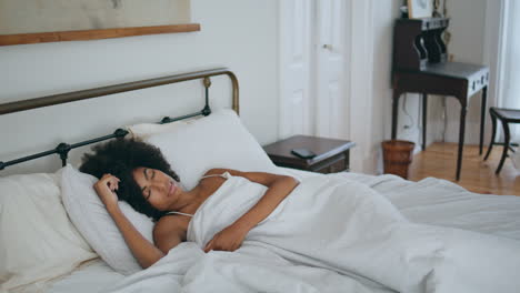 curly woman sleeping bed at morning. black skin lady napping home laying pillow