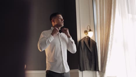 groom adjusts bow tie, preparing to go to the bride, businessman in white shirt, wedding day