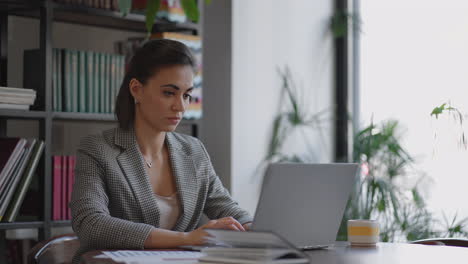 retrato de una mujer hispana escribiendo en una computadora portátil envía un correo electrónico a un cliente y está contenta con el resultado. mujer de negocios sentada en la mesa