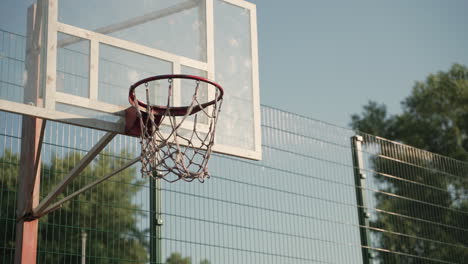 close up of outdoor basketball hoop with net and backboard in a sunny day