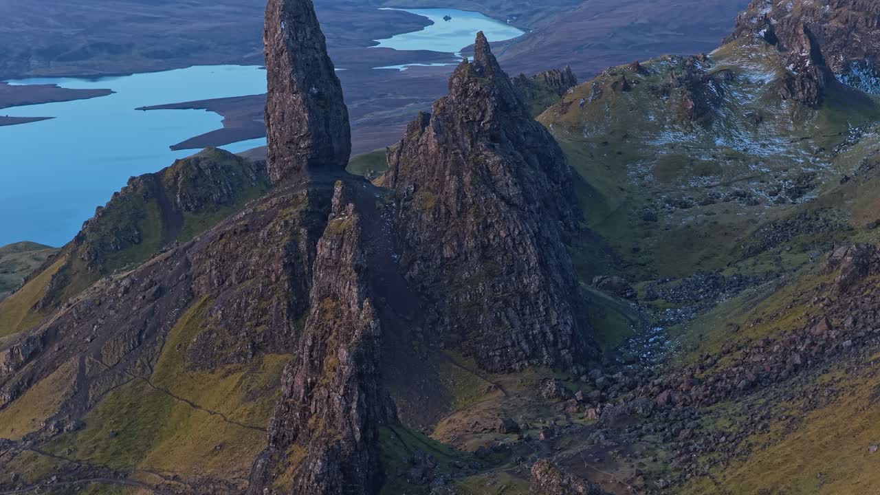 Drönare som flyger bakåt och avslöjar klippformationen Old Man of Storr vid soluppgången.