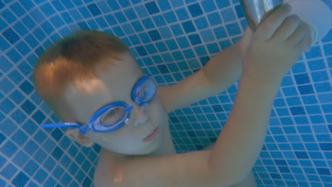 boy in goggles holding breath in swimming pool