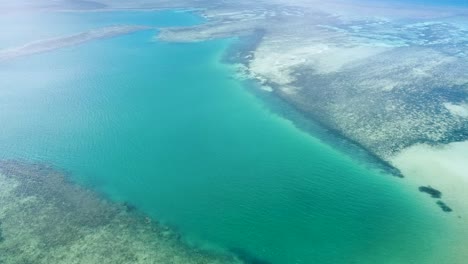 Aerial-drone-rising-above-expansive-coral-reefs-on-tropical-island-Timor-Leste,-South-East-Asia