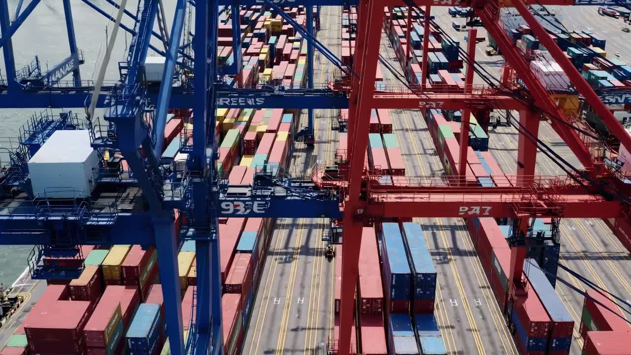 Luftfoto af travl fragthavn med portalkraner, der flytter containere