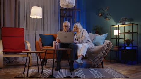 una pareja de ancianos felices usando una computadora portátil hablando leyendo discutiendo noticias de internet en casa
