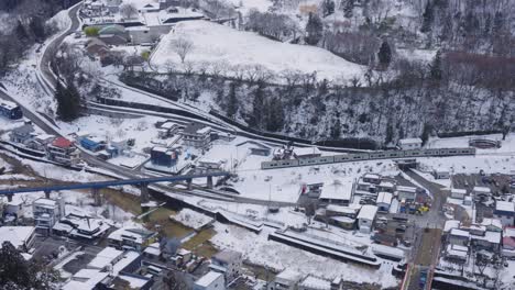 train travels across japanese countryside in the winter, passing yamadera temple