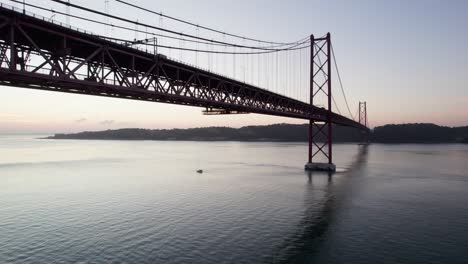 small boat underneath the suspension bridge in portugal