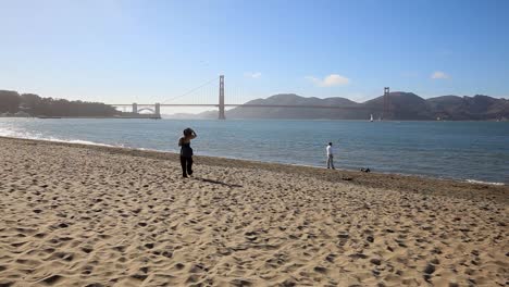 Mujer-Caminando-Por-La-Orilla-En-Crissy-Field-Mientras-Mira-A-Su-Perro