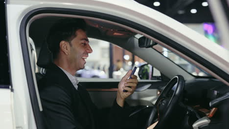 businessman using smartphone inside a car at a car show