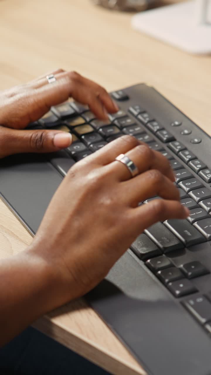 Vertical video Person at home office desk typing on PC keyboard next to coffee mug, close up
