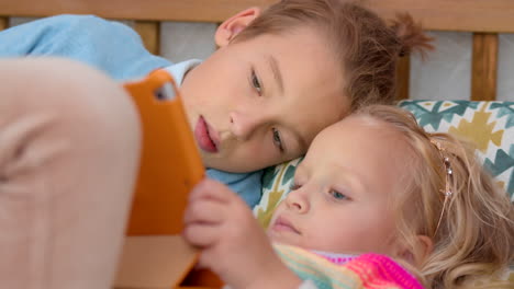 brother and sister playing games on touch pad at home