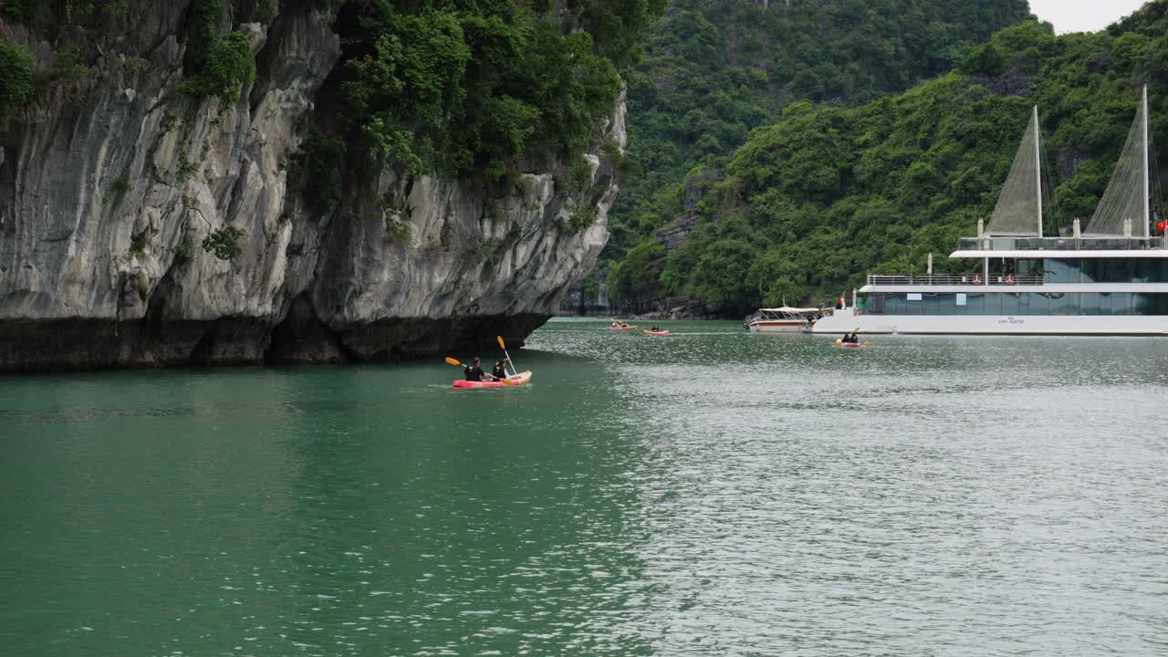 kayak en la bahía de halong con acantilados rocosos y barco en el fondo en vietnam