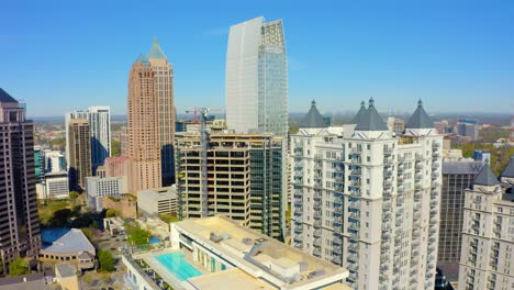 drone aéreo disparado lentamente girando en sentido contrario a las agujas del reloj alrededor de rascacielos cerca de piedmont park en el centro cerca del centro de atlanta, georgia en un día soleado con cielos azules
