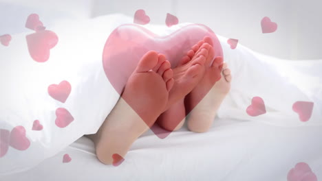 couple lying in bed playing with feet