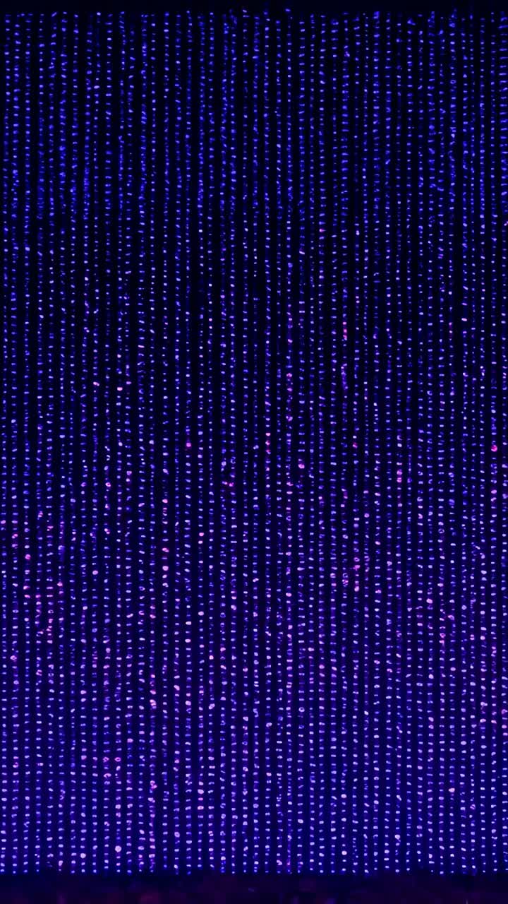 Vertical video: Shifting LED curtain changing purple to white as sequence triggers slow stage glow