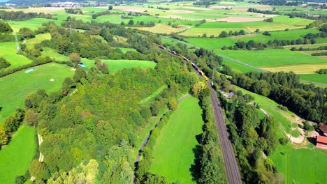 aerial-drone-above-freight-train-passing-by-a-rural-village-4k