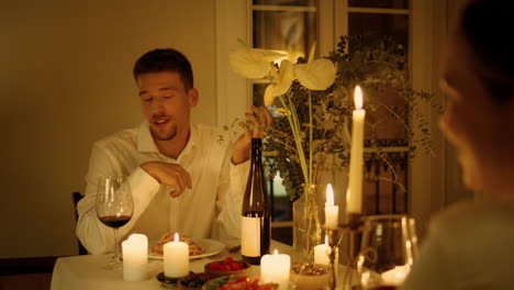 hombre alegre hablando velas cena de cerca. chico hablando en una cita romántica