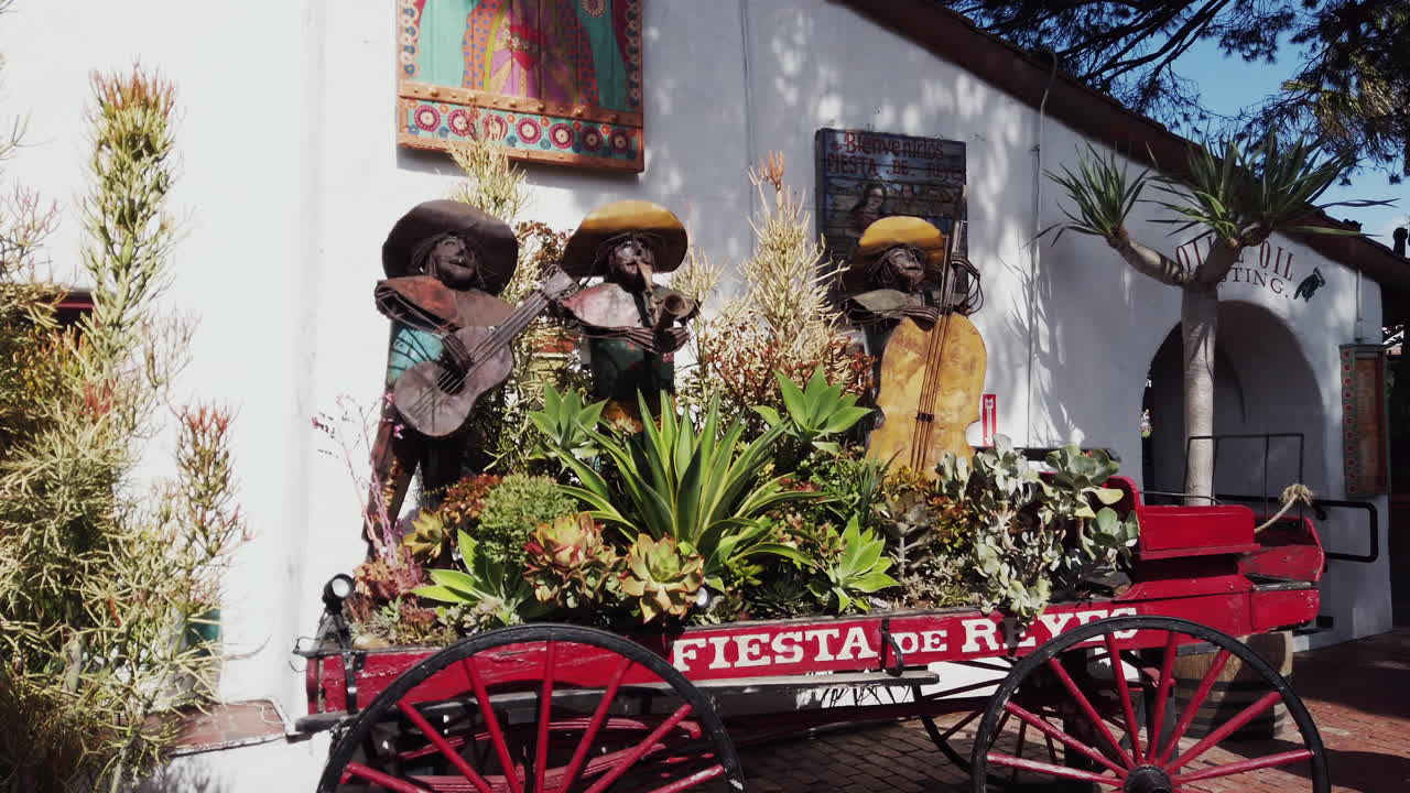 Three metal mariachi sculptures play instruments among lush succulents in a rustic wagon at Fiesta de Reyes