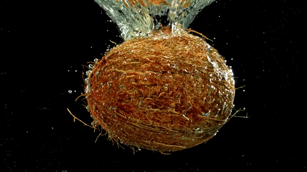 Cocco fresco che cade nell'acqua al rallentatore con schizzi