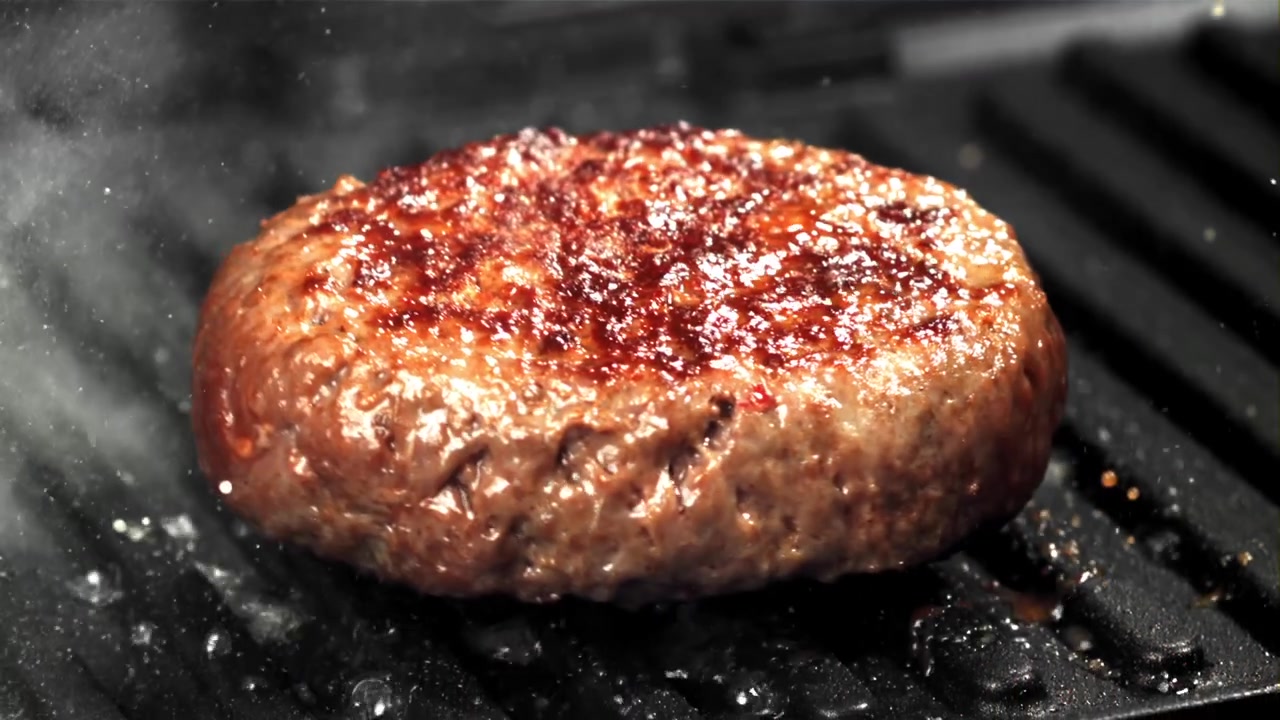 Sydende burgerbøf, der steger på en varm grill