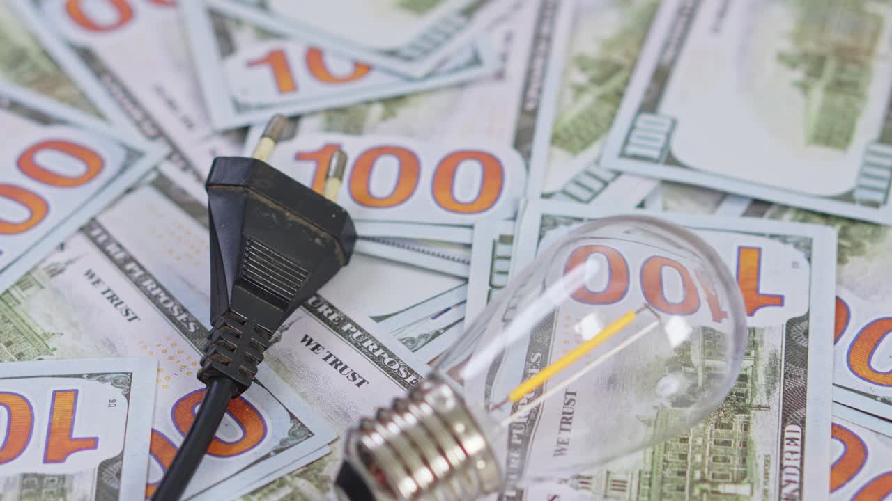 Energy saving concept with light bulb and power plug on dollar bills