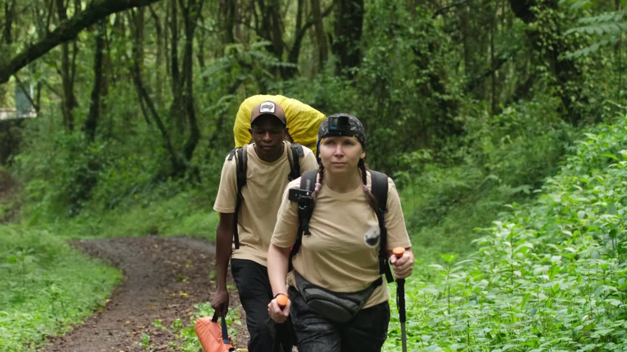 A tourist with a large backpack walks with a guide during a hike