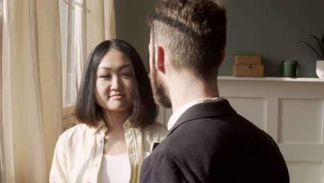 Woman-Holding-Coffee-Mug-And-Debating-With-A-Man-While-Standing-Near-The-Window-In-The-Morning