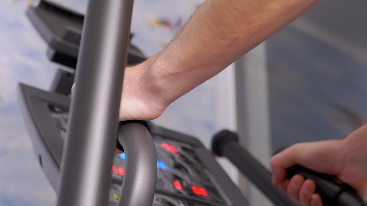 спортсмен тренируется на эллиптическом тренере дома, наблюдая за сердечным ритмом на мониторе