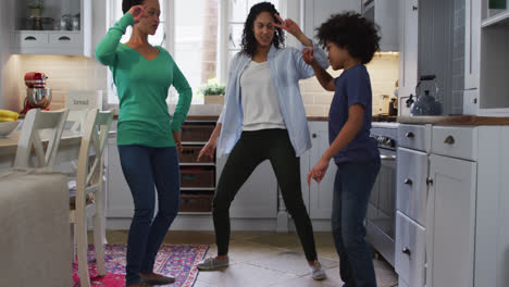 mixed race lesbian couple and daughter dancing in kitchen