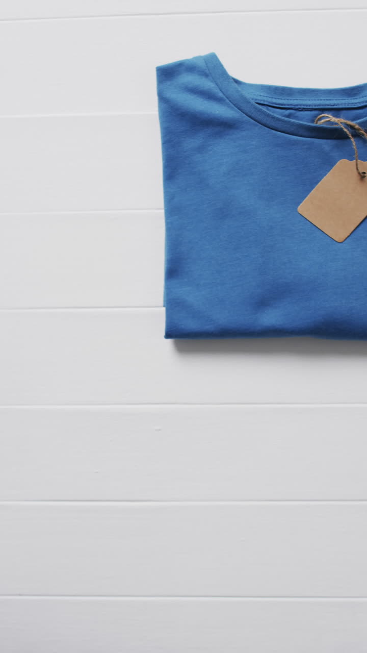 Vertical video of blue folded t shirt and copy space on white background