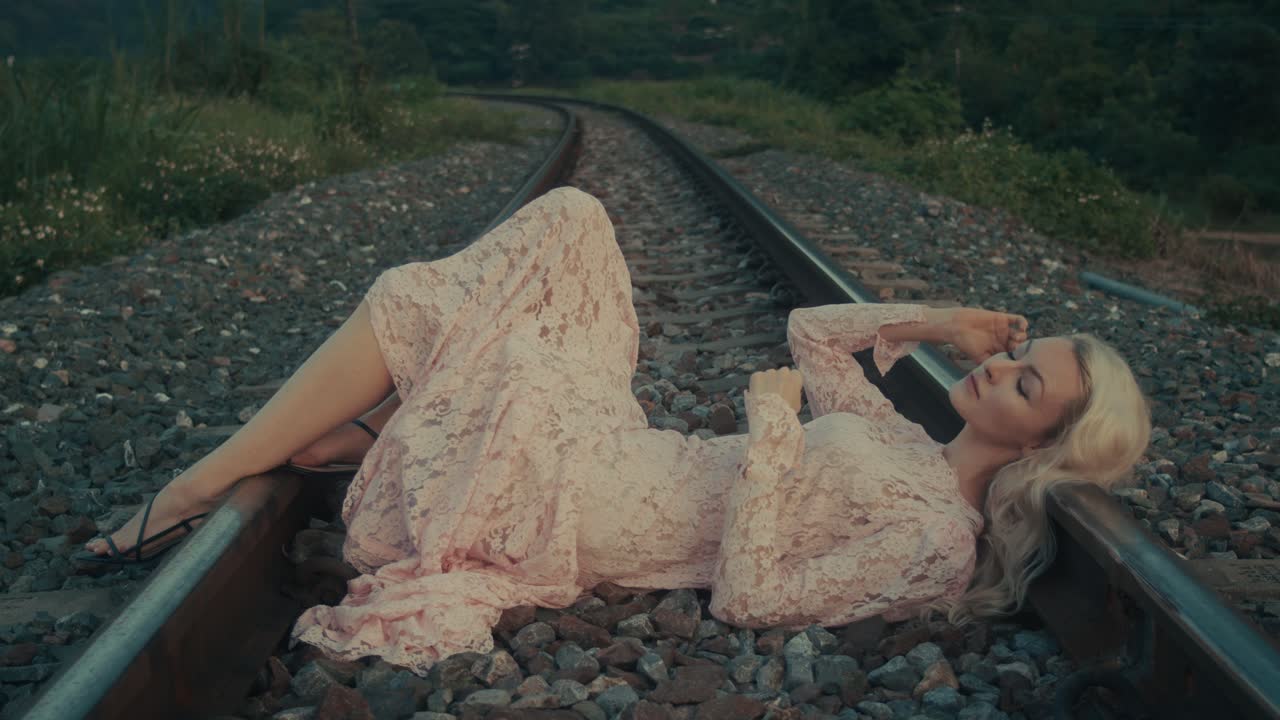 Woman in a Pink Lace Dress on Train Tracks